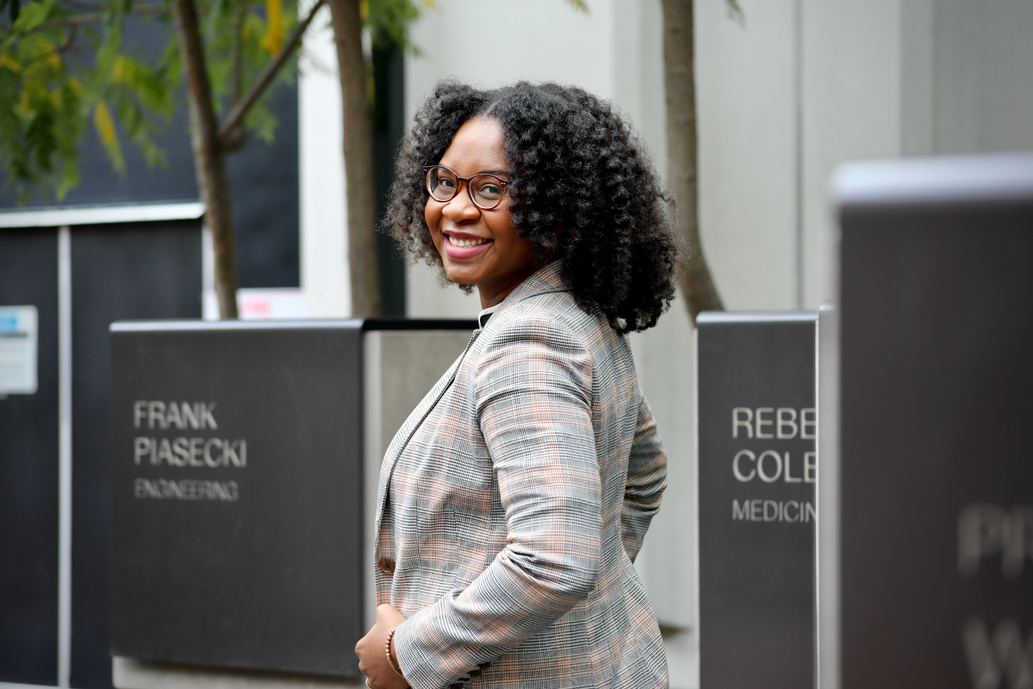 Dr. Atasha Jordan smiling outdoors in a plaid blazer